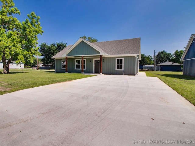 view of front facade with driveway, a front lawn, and a shingled roof