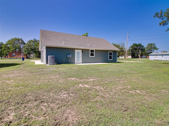 rear view of property featuring a yard, a patio, roof with shingles, and central AC unit