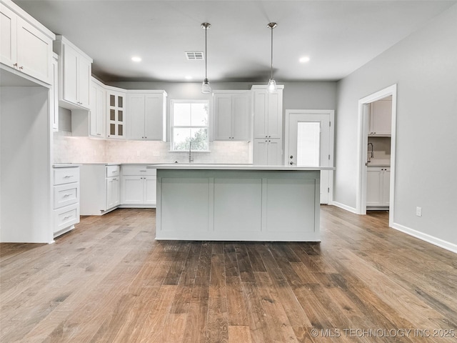 kitchen featuring white cabinetry, wood finished floors, visible vents, and a center island