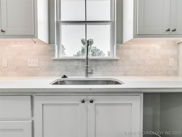 kitchen with white cabinetry, light countertops, tasteful backsplash, and a sink