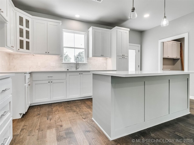 kitchen with light countertops, white cabinets, dark wood-style floors, and a sink