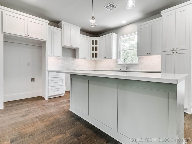 kitchen featuring visible vents, backsplash, white cabinetry, glass insert cabinets, and dark wood-style flooring