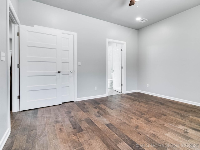 unfurnished bedroom with visible vents, a ceiling fan, ensuite bath, dark wood-style floors, and baseboards