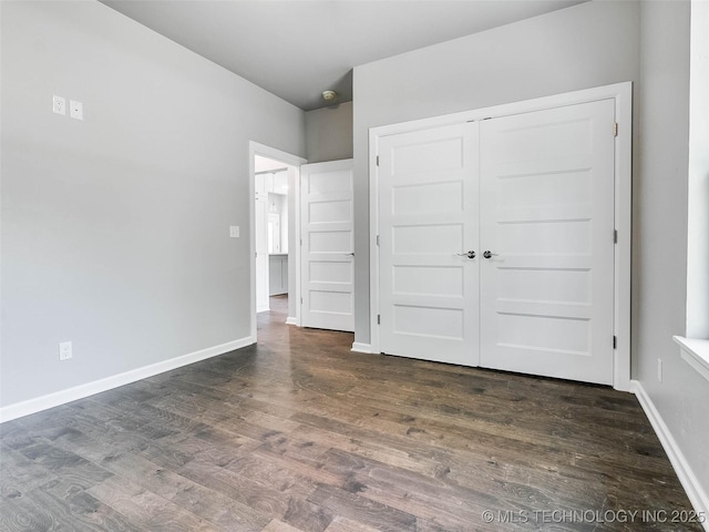 unfurnished bedroom with wood finished floors, baseboards, and a closet