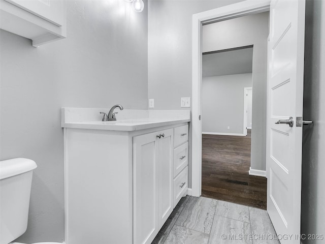 half bathroom with vanity, toilet, and baseboards