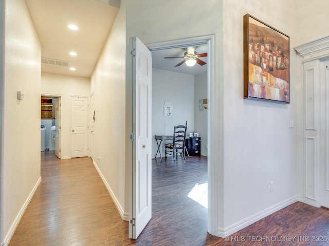 corridor featuring visible vents, baseboards, and wood finished floors