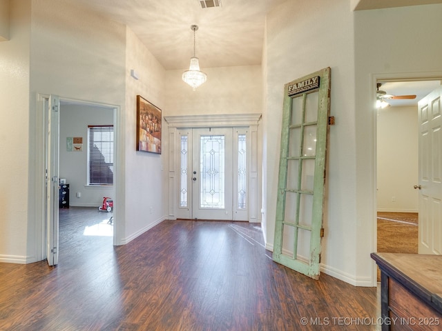 entryway featuring wood finished floors, baseboards, and a towering ceiling