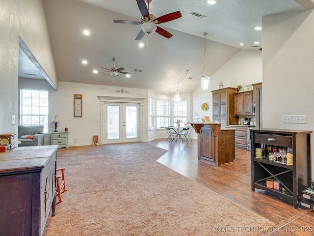 kitchen with a kitchen island, open floor plan, french doors, a breakfast bar area, and brown cabinetry