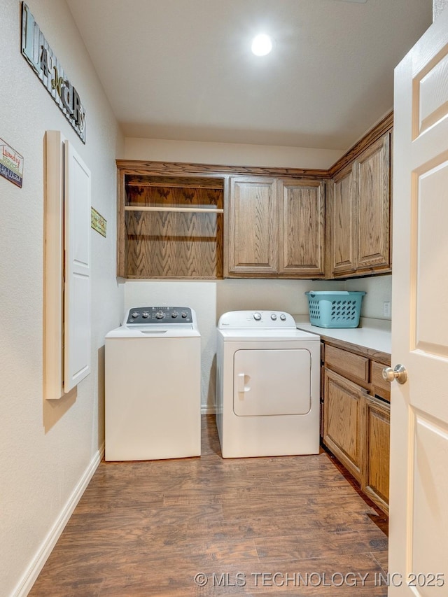 clothes washing area featuring baseboards, cabinet space, separate washer and dryer, and dark wood-style floors