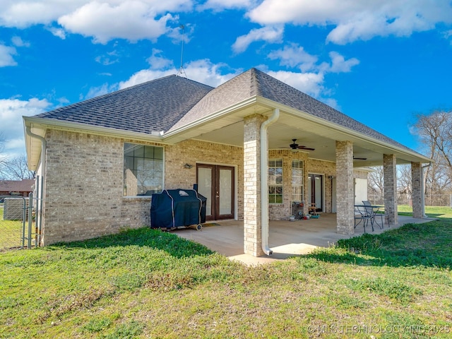 back of property featuring a patio area, a yard, french doors, and roof with shingles