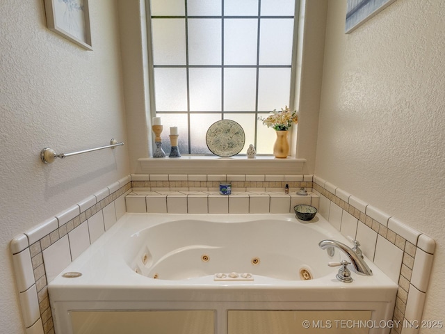 bathroom featuring a jetted tub and a textured wall