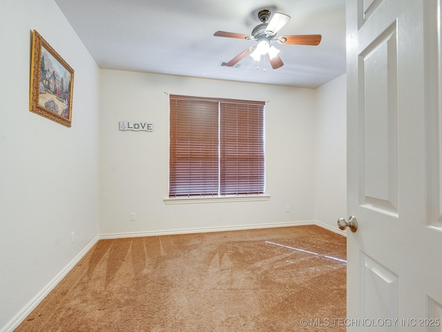 carpeted empty room with visible vents, baseboards, and ceiling fan