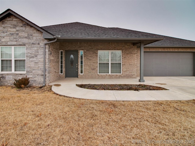 single story home with a front lawn, stone siding, roof with shingles, an attached garage, and brick siding