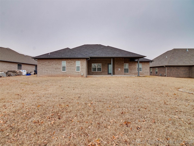 back of property featuring brick siding and a shingled roof