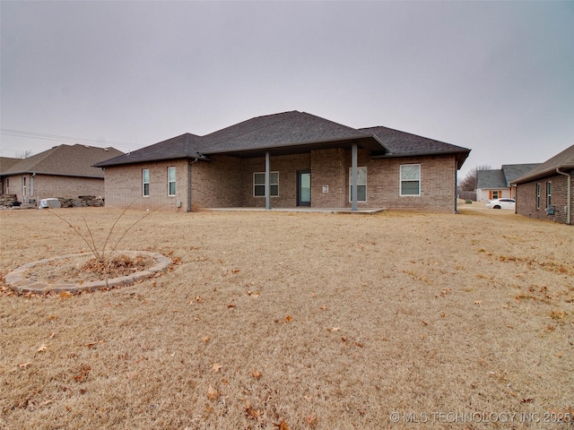 back of house with brick siding and a shingled roof