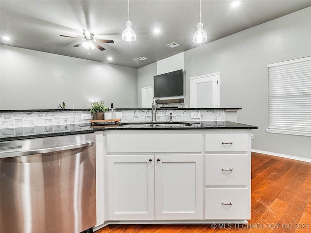 kitchen with dark stone countertops, visible vents, a sink, white cabinets, and stainless steel dishwasher