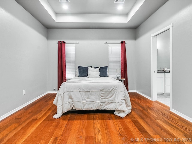 bedroom with visible vents, wood finished floors, and baseboards