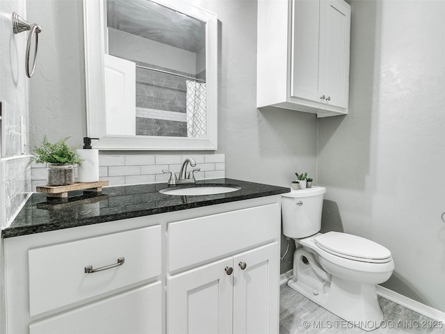 full bathroom with vanity, toilet, baseboards, and backsplash