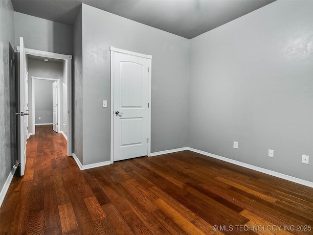 spare room with baseboards and dark wood finished floors