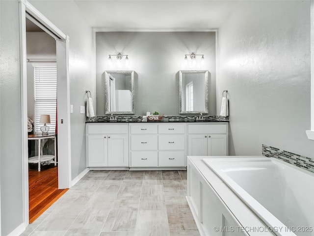 full bath with a sink, a bath, and double vanity