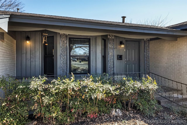 property entrance with board and batten siding, covered porch, and brick siding