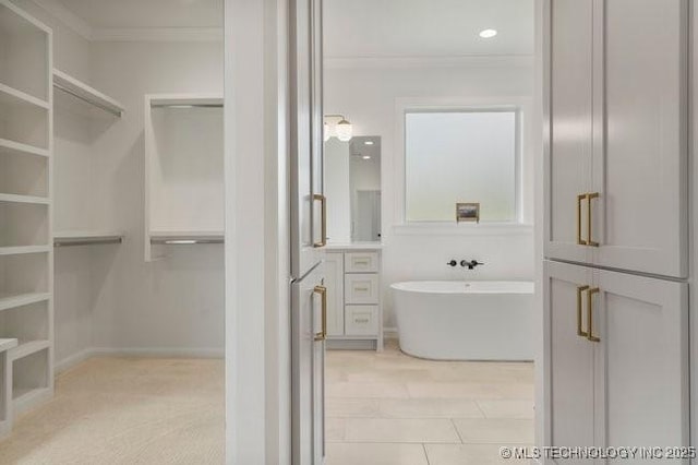 full bathroom with a freestanding bath, a walk in closet, and ornamental molding