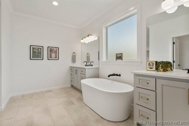 full bath featuring a freestanding tub, two vanities, baseboards, and ornamental molding