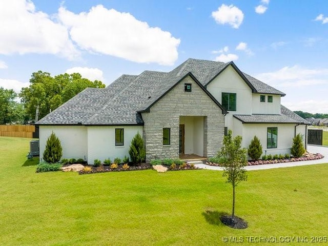 view of front of home with a front lawn, fence, stone siding, and roof with shingles