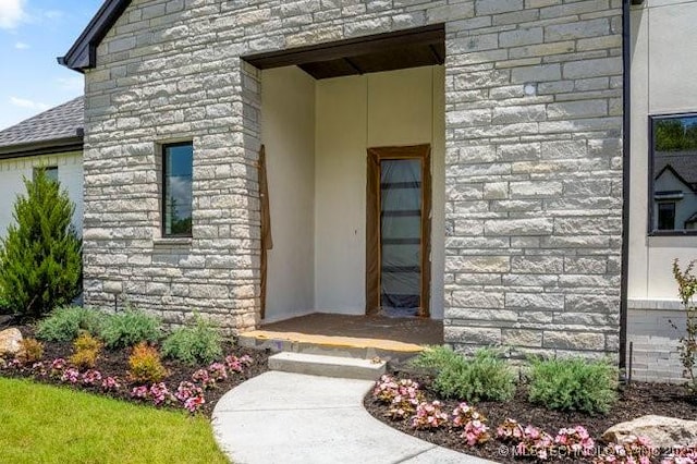 property entrance with stone siding and a shingled roof