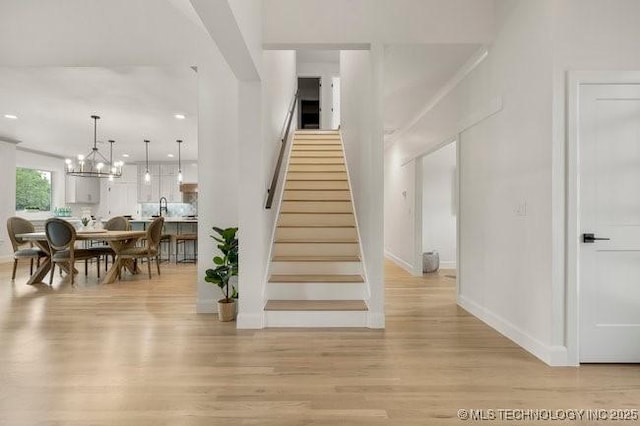 stairway featuring recessed lighting, baseboards, a notable chandelier, and wood finished floors