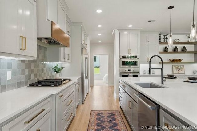 kitchen featuring stainless steel appliances, a sink, light countertops, decorative light fixtures, and backsplash