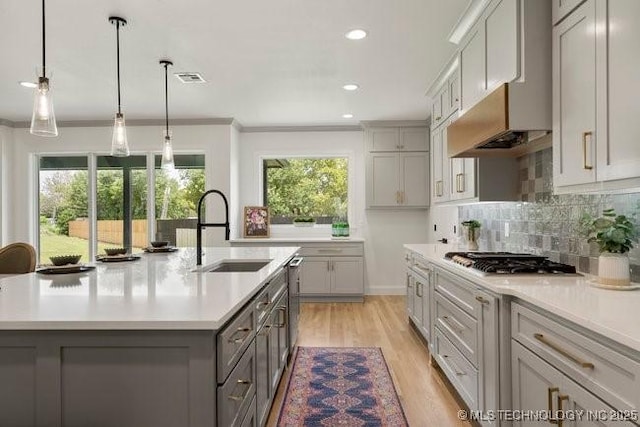 kitchen with gray cabinetry, stainless steel appliances, light countertops, and a sink