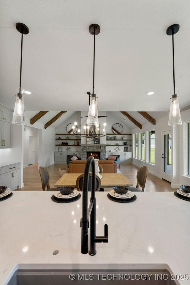 interior details featuring a stone fireplace, beamed ceiling, and wood finished floors