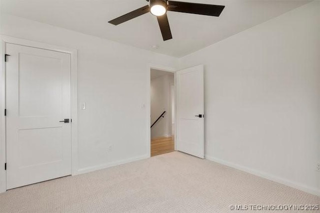 unfurnished bedroom with light colored carpet, baseboards, and ceiling fan