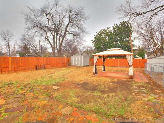 view of yard with a storage shed, a gazebo, an outbuilding, and a fenced backyard