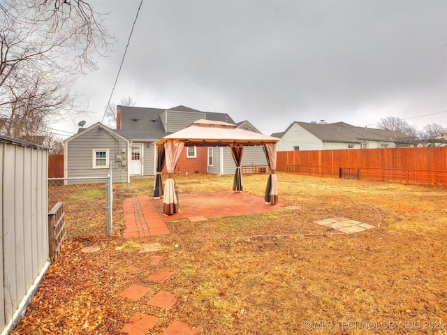 rear view of property featuring a gazebo, a fenced backyard, and a patio area