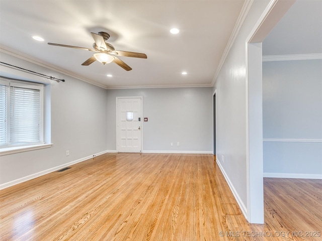 empty room featuring ornamental molding, baseboards, visible vents, and light wood-type flooring