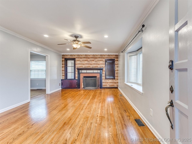 unfurnished living room featuring visible vents, plenty of natural light, a fireplace, and light wood finished floors