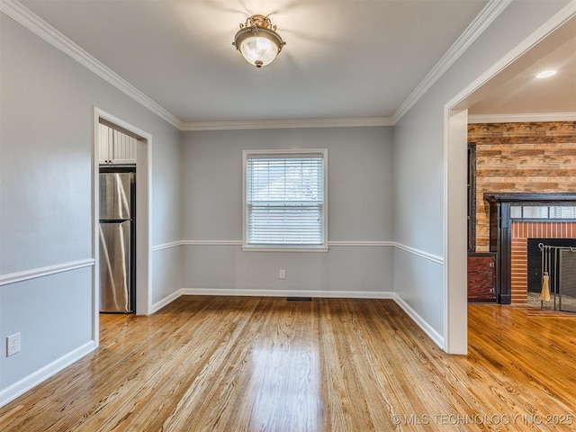 spare room featuring baseboards, wood finished floors, a fireplace, and crown molding