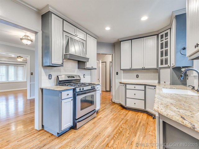 kitchen featuring ornamental molding, a sink, light wood finished floors, custom exhaust hood, and stainless steel gas range