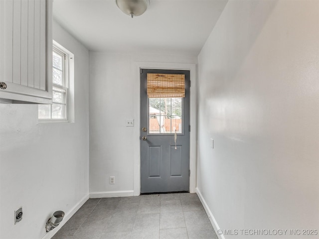 doorway featuring light tile patterned floors and baseboards