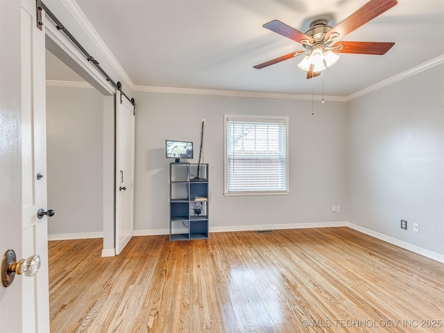 unfurnished bedroom featuring a barn door, baseboards, ornamental molding, and light wood finished floors