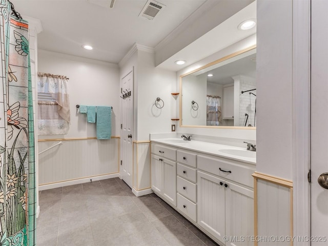 bathroom with a sink, visible vents, double vanity, and crown molding