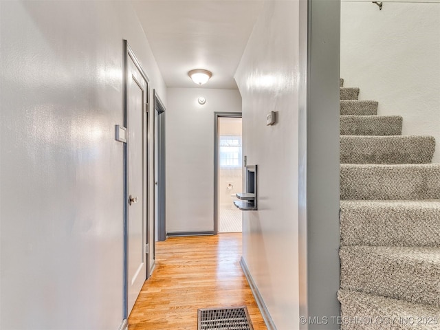 corridor with visible vents, stairs, and light wood-type flooring