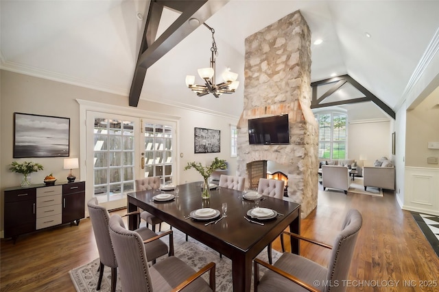 dining room featuring a stone fireplace, lofted ceiling, wood finished floors, and ornamental molding