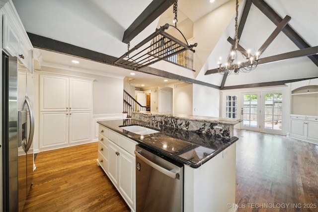 kitchen with open floor plan, beamed ceiling, light wood-type flooring, stainless steel appliances, and a sink