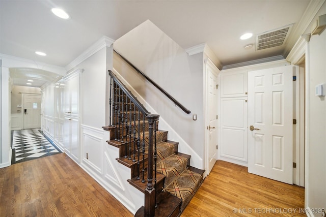 interior space featuring visible vents, wood finished floors, ornamental molding, and stairs