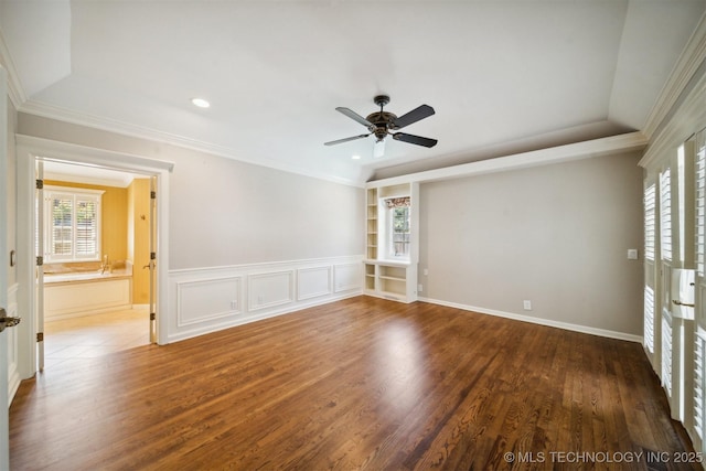 spare room featuring ceiling fan, built in shelves, wood finished floors, and ornamental molding