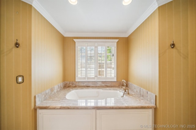 bathroom featuring ornamental molding, wallpapered walls, a garden tub, and a sink