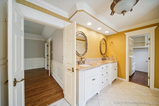 bathroom with a sink, double vanity, crown molding, and tile patterned flooring